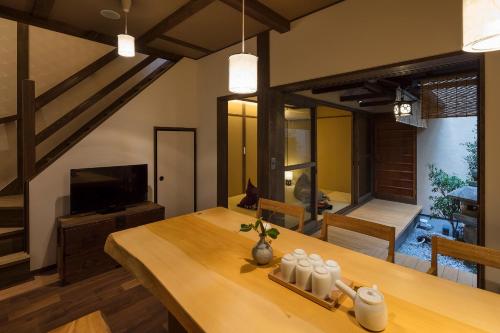 a dining room with a wooden table and a television at Fujinoma Machiya House in Kyoto