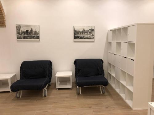 two chairs are sitting in a room with a shelf at San Lorenzo University flat in Rome