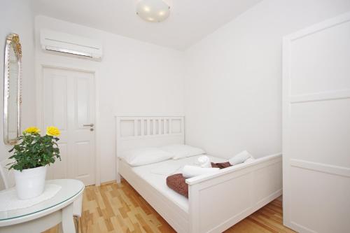 Dormitorio blanco con cama y mesa en Apartment Esperanca - Zadar, en Zadar