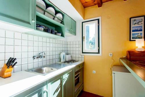 a kitchen with green cabinets and a sink at Villa Kalypso and Villa Kirki in Skopelos Town