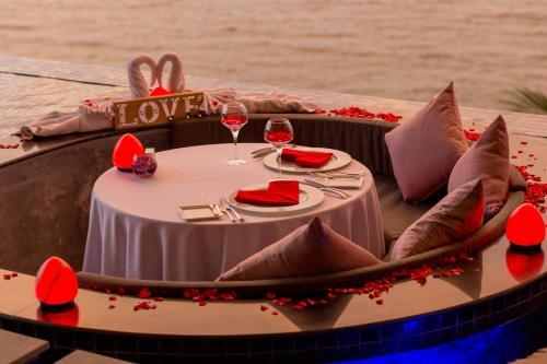 Cape Sienna Phuket Gourmet Hotel & Villas - SHA Extra Plus في شاطئ كامالا: طاولة مع كؤوس النبيذ والزهور الحمراء عليها