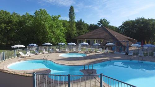 a large swimming pool with chairs and umbrellas at VVF Bourgogne Auxois Morvan in Semur-en-Auxois