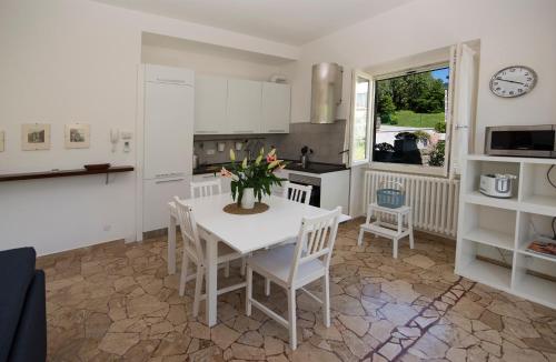 a kitchen with a white table and chairs and a table at Vitali Apartment JR in Bellagio