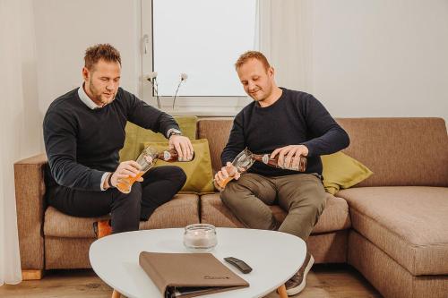 two men are sitting on a couch playing bottles at Appartements Almnest in Schladming