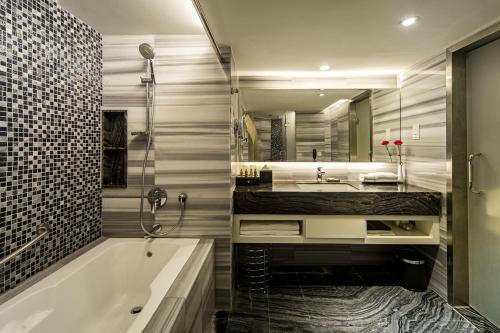 een badkamer met een bad, een wastafel en een spiegel bij Promenade Hotel Kota Kinabalu in Kota Kinabalu