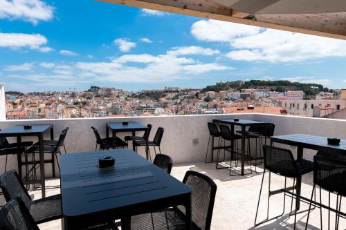 a patio with tables and chairs and a view of a city at Lisboa Pessoa Hotel in Lisbon