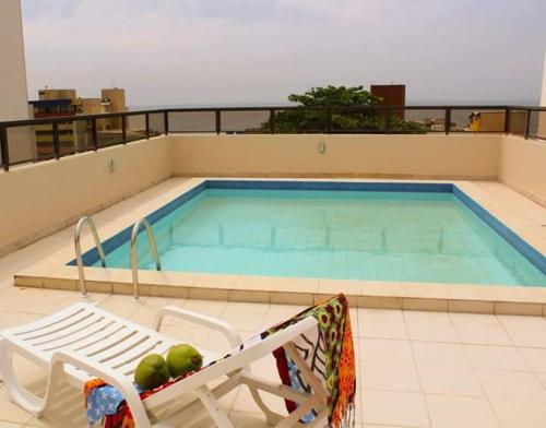 a swimming pool on top of a building with a chair at Residencial Porto Farol in Salvador