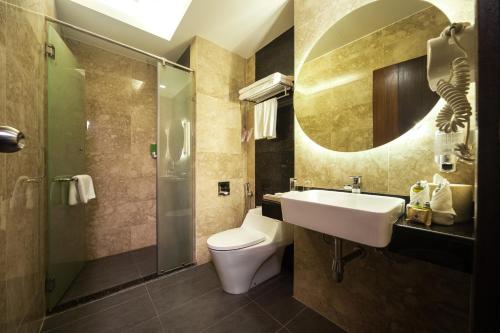 a bathroom with a sink and a toilet and a mirror at Promenade Hotel Bintulu in Bintulu