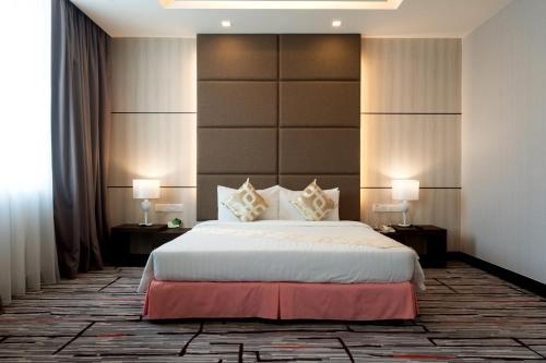 a bedroom with a large bed with two tables and two lamps at Promenade Hotel Bintulu in Bintulu