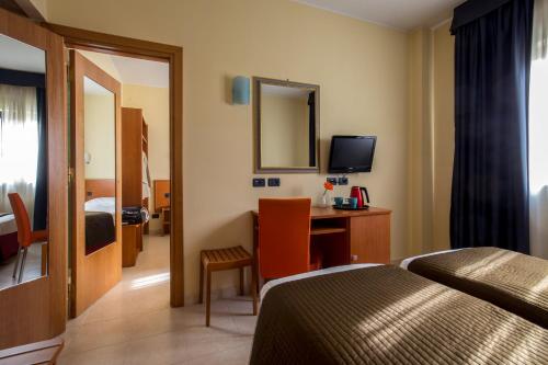 a hotel room with a bed and a desk with a mirror at Best Western Blu Hotel Roma in Rome