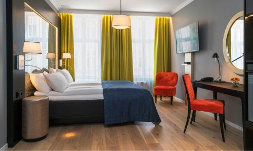 a hotel room with a bed, chair, and nightstand at Thon Hotel Spectrum in Oslo