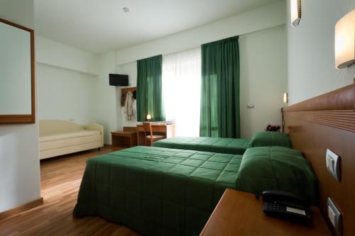 a bedroom with two green beds and a couch at Hotel Donnini in Assisi