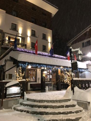 a building with christmas lights and stairs in the snow at Hotel Edelweiss in Breuil-Cervinia