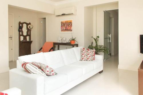 un sofá blanco en una sala de estar con almohadas en Mallorca Penthouse - cobertura com piscina privativa e vista pro mar, en Bombinhas