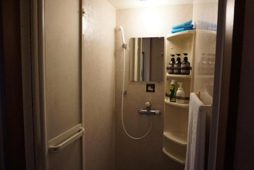 a bathroom with a shower and a sink with a mirror at Yokohama Minatomirai Manyo Club in Yokohama