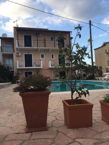 a building and three pots with plants in front of it at Avgoustina Venus Studios in Benitses