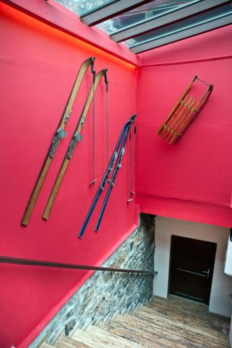 three skis are hanging on a red wall at Chalet Lithos in Palaios Agios Athanasios