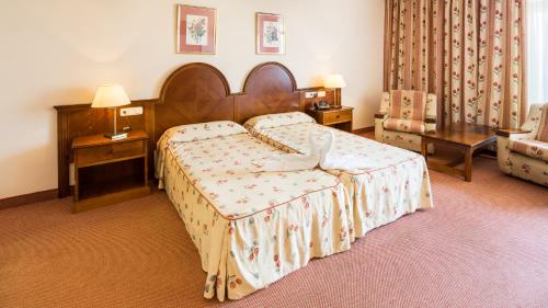 a bedroom with a bed and two tables and a chair at Complejo BLUESEA Puerto Resort compuesto por Hotel Canarife y Bonanza Palace in Puerto de la Cruz