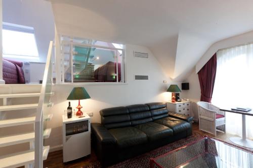 a living room with a black leather couch and a staircase at Hotel Approach in Knokke-Heist