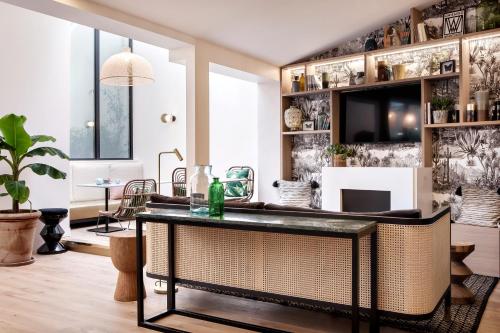 a living room with a table and a tv at Doisy Etoile - Orso Hotels in Paris