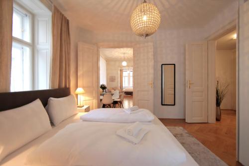 - une chambre avec un grand lit blanc et un lustre dans l'établissement City Stay Vienna – Spittelberg, à Vienne