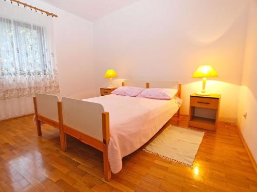 a bedroom with a bed and two lamps on two tables at Apartments Dvorine 1210 in Banjole