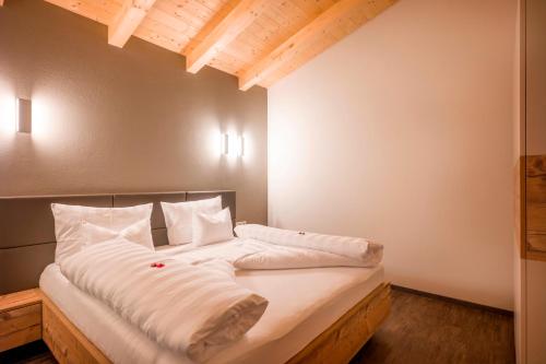 a bed with white sheets and pillows in a room at Apart Dengg in Mayrhofen
