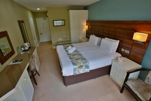 a bedroom with a large bed with a wooden headboard at Quorn Grange Hotel in Loughborough