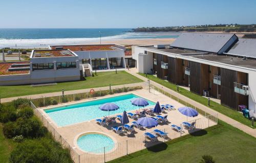 an overhead view of a pool with chairs and umbrellas at Résidence Odalys Fleur de Sel in Guidel-Plage