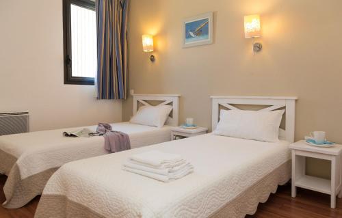 two beds in a room with white sheets at Résidence Odalys Fleur de Sel in Guidel-Plage