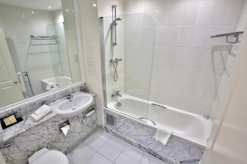 a bathroom with a sink and a tub and a toilet at Quorn Grange Hotel in Loughborough