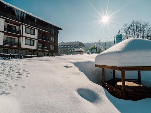 a snow covered building with the sun in the background at Green Life Bansko in Bansko