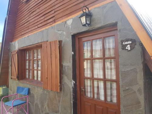een huis met twee deuren en een blauwe stoel buiten bij Cabañas Melipal Copahue in Copahue