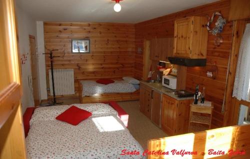 サンタ・カテリーナ・ヴァルフルヴァにあるBaita Stelvioのベッドルーム1室(ベッド2台付)、木製の壁のキッチン