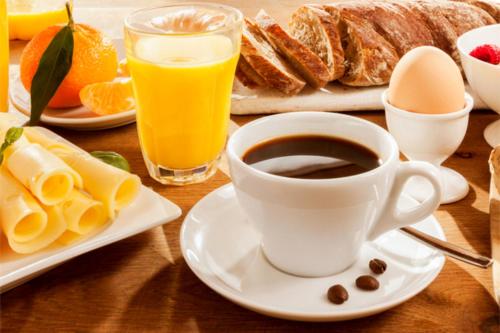 a table with a cup of coffee and a plate of breakfast foods at Hotel Approach in Knokke-Heist