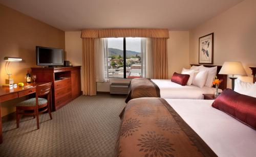 a hotel room with two beds and a desk and a television at Coast Wenatchee Center Hotel in Wenatchee