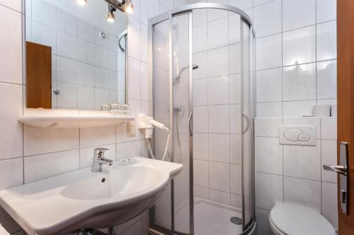 a white bathroom with a sink and a shower at Pension Margarete in Zell am See
