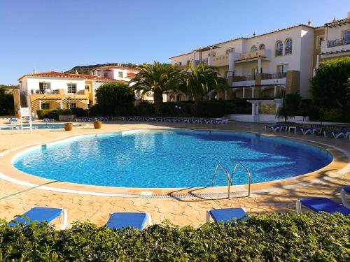 a large swimming pool with chairs and buildings at Club House CVL in Luz