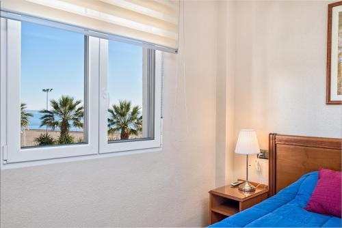 een slaapkamer met een bed en een raam met palmbomen bij WintowinRentals La Posada del Mar in Rincón de la Victoria