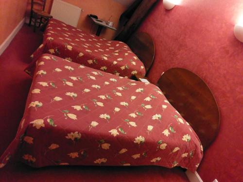 a bed with a red blanket with flowers on it at Logis de L'Europe Restaurant Le Cepage in Corbigny