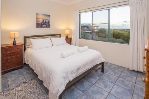 a bedroom with a bed and a large window at Kilifi Beach House in Gnarabup