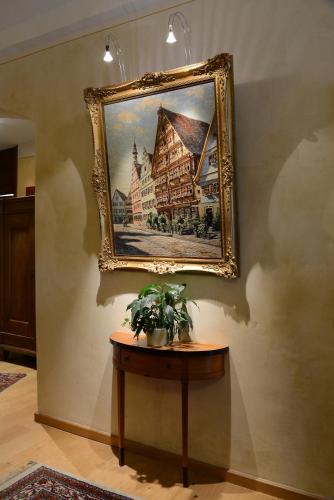 a painting of a building on a wall with a table at Hotel Deutsches Haus in Dinkelsbühl