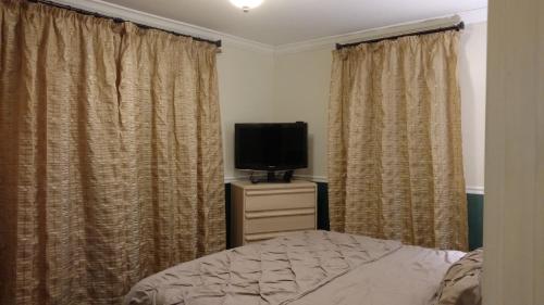 a bedroom with a bed and a tv and curtains at Homestay in Westwood 97909 in Cincinnati