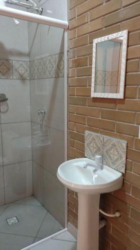 a bathroom with a sink and a shower with a mirror at Chales Ilhabela ll in Ilhabela