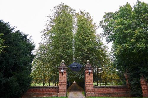a brick gate with a large tree behind it at The Oaksmere in Eye