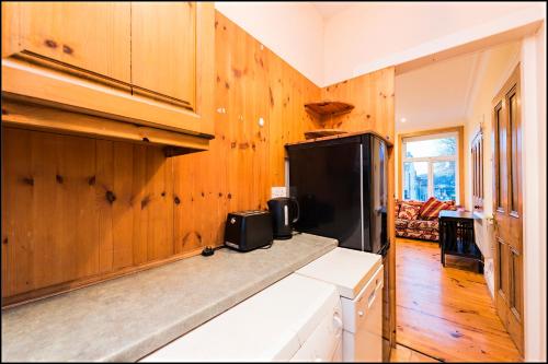 ダブリンにあるDrumcondra Junction Apartmentsの木製の壁と黒い冷蔵庫付きのキッチン