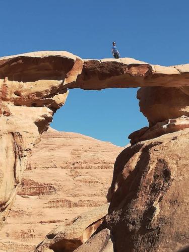a man standing on top of a rock formation at Climbers House in Wadi Rum in Wadi Rum