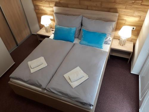 a bedroom with a bed with two blue pillows at Apartment Jasna - Lucky in Demanovska Dolina