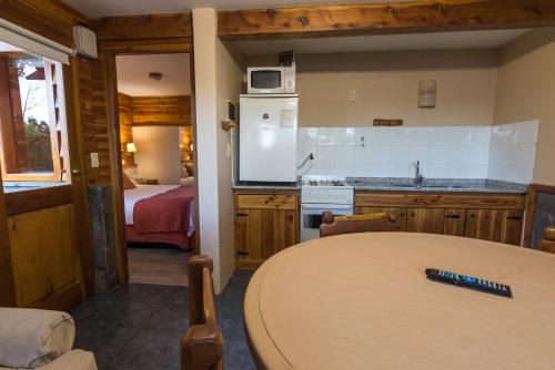 a kitchen with a table and a room with a bed at Cabañas Las Marias Del Nahuel in San Carlos de Bariloche