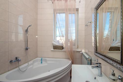 a white bathroom with a tub and a mirror at Mini Hotel Ryleev in Kharkiv